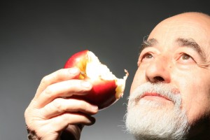 a senior gentleman is eating red apple